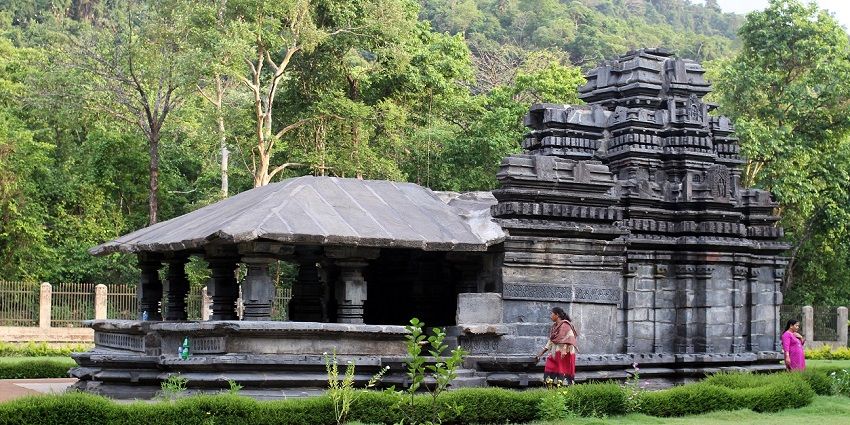 Exteriors of Tambdi Surla Mahadev Temple with women relaxing.