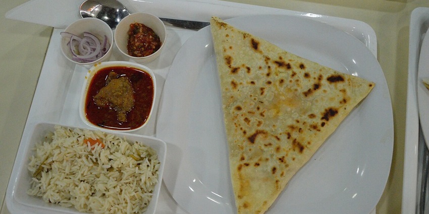 A plate of Rice Tehri served with curry, chapati and salad on the side.