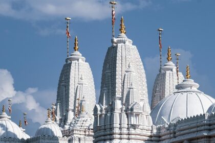 Image of an astonishing white temple in Agra alongside a road with devotees around it.