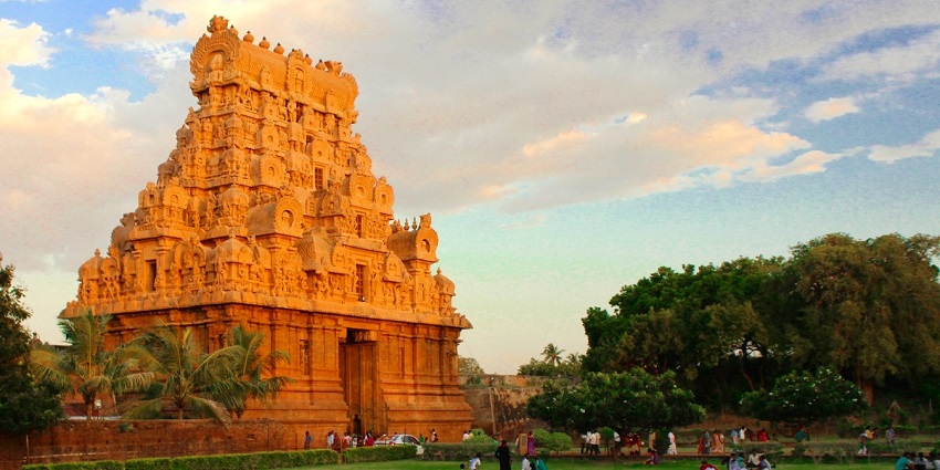 Gopuram of Brihadisvara Temple with intricate carvings and people sitting on the lawn
