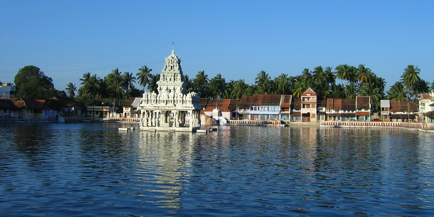 A distant view of the marvellous Thanumalayan Temple is showcased across a water body.