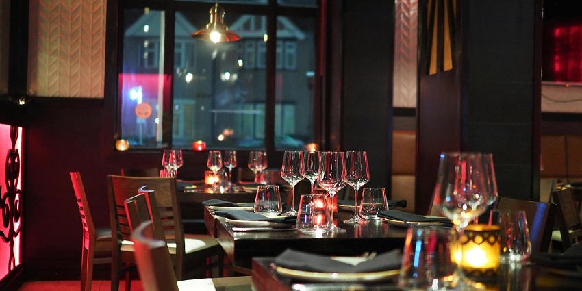 Image of dining tables decorated with wine glassed and plate with dim light experience