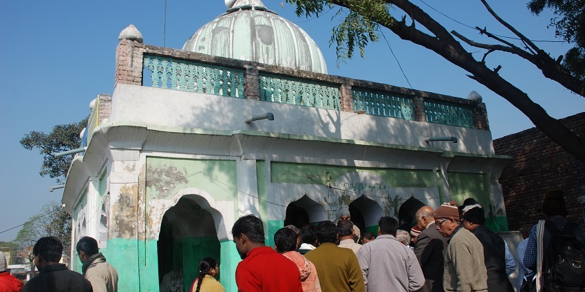 A picture of a Dargah with many devotees seen standing in queue and seeking blessings