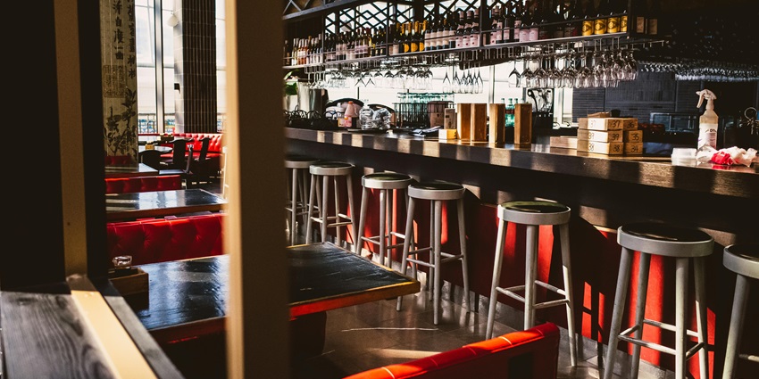 Cozy modern restaurant interior with red seating, wooden counter, and ambient lighting