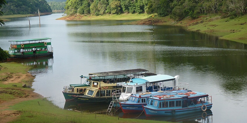 A picture of boats parked along the shore of a water body with lush green landmass in the background