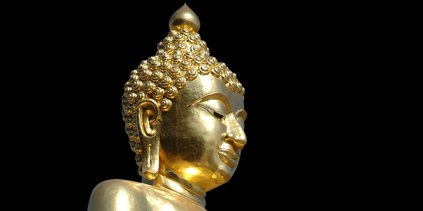 Image of a serene Buddha statue situated outdoors depicted in a seated meditation pose.