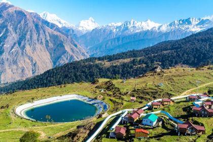 A scenic view of Auli featuring snow covered mountains under a clear blue sky