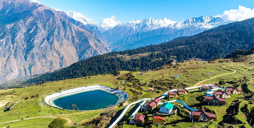 A scenic view of Auli featuring snow covered mountains under a clear blue sky