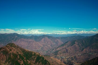 A breathtaking vista of majestic peaks, rustic terrains, and misty clouds in Uttarakhand.