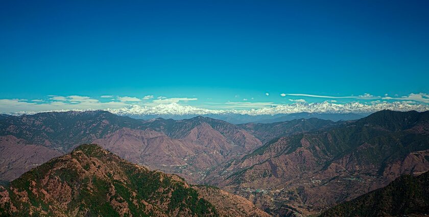 A breathtaking vista of majestic peaks, rustic terrains, and misty clouds in Uttarakhand.