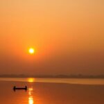 A Lakeside view represents the early sunrise over the city's horizon and Fishermen