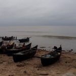 A picture of a beach in Digah with boats on shore side and a vast sea in the background