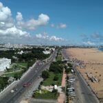 Aerial view of Chennai city with buildings, roads, and greenery visible from above.