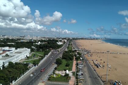 Aerial view of Chennai city with buildings, roads, and greenery visible from above.