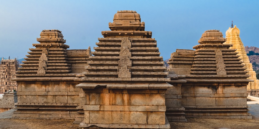 Pieces from the ruins of a Jain temple in the background featuring new construction
