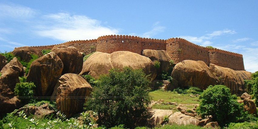 Tirumayam Fort elevated with its massive stone walls surrounded by a green landscape.