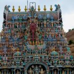 A view of the Thiruparankundram Temple adorned with intricate carvings under clear skies.