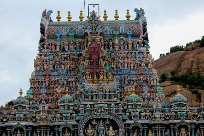 A view of the Thiruparankundram Temple adorned with intricate carvings under clear skies.