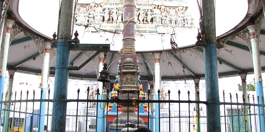 Interior of the Thiruporur Murugan Temple with a flagpole and gopuram in the background.
