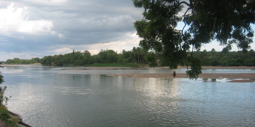 A breathtaking view of a river in Thiruvaiyaru surrounded by lush green meadows.