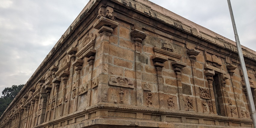 A photo of an ancient temple arcade featuring a row of tall, ornate stone columns.