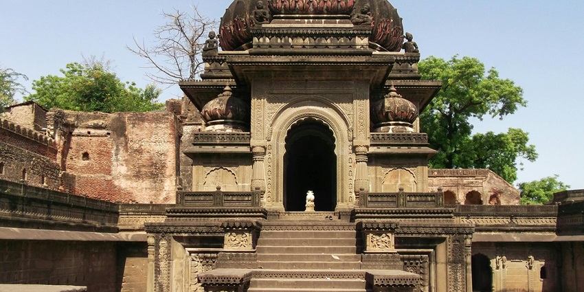 A stone staircase leading up to Tirunallar Saneeswaran Temple, surrounded by greenery under a clear blue sky