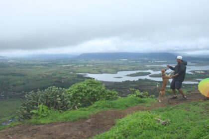 A scenic picture of a man with his dog trekking in Maharashtra amidst the most scenic monsoon.