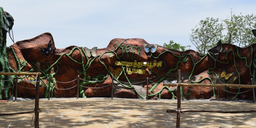 Entrance to tropical butterfly conservatory with architected butterflies and sign.