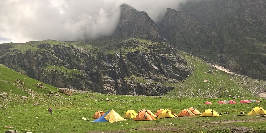 A misty mountain trail with trekkers walking along a ridge, overlooking valleys and waterfalls, one of the best things to see in Igatpuri.