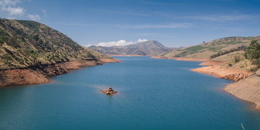 Image of a lake surrounded by hills under beautiful blue sky - a scenic place to visit near Ooty
