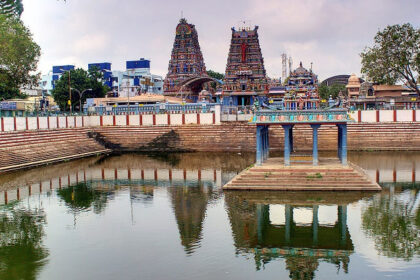 Water tank at Vadapalani Murugan Temple, surrounded by temple structures and gopurams.