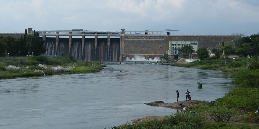 People at the Vaigai Dam surrounded by greenery with water flowing through the structure