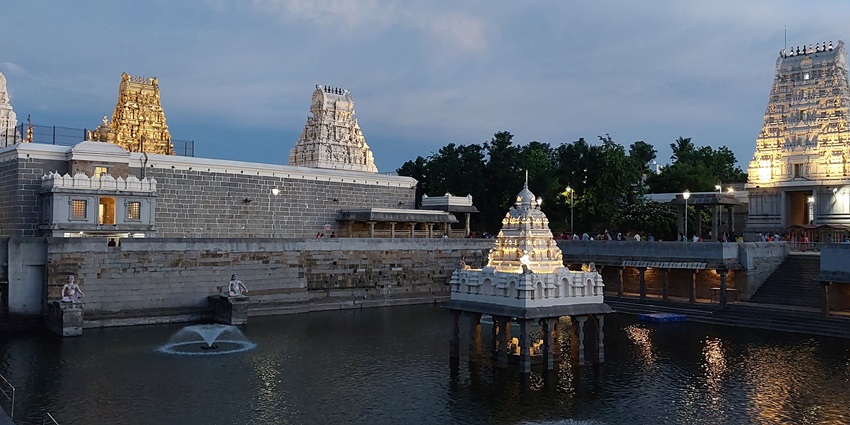 A picture of a temple complex in Chennai with a holy pond and lit-up buildings