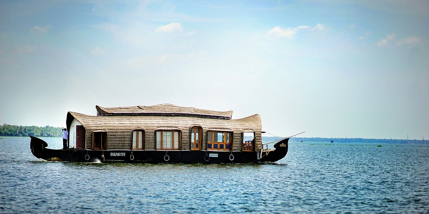 A serene view of a houseboat sailing on the shimmering blue waters of Tamil Nadu.