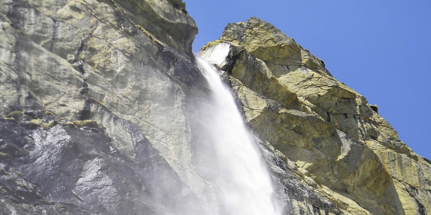Vasudhara Falls near the temple, a scenic spot surrounded by mountains.