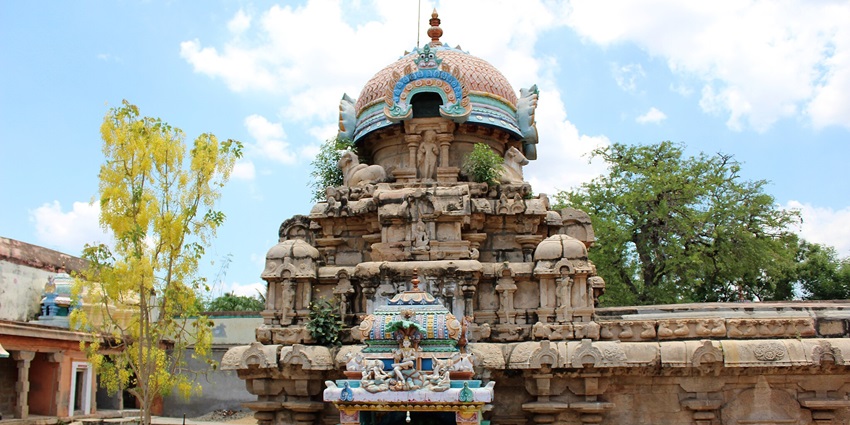Exterior view of the Vedapureeswarar Temple with vibrant traditional gopuram and a tree