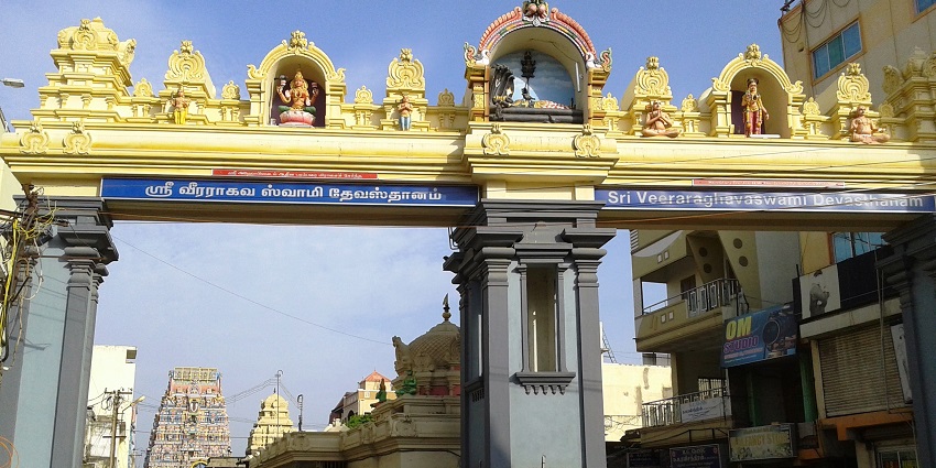 Designed entrance gate to the Veeraraghava Perumal temple with people walking by.
