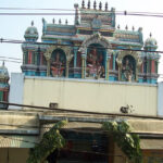 Outside of Vekkaliyamman Temple featuring idols of deities and an entrance decorated with leaves hanging.