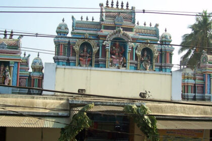 Outside of Vekkaliyamman Temple featuring idols of deities and an entrance decorated with leaves hanging.