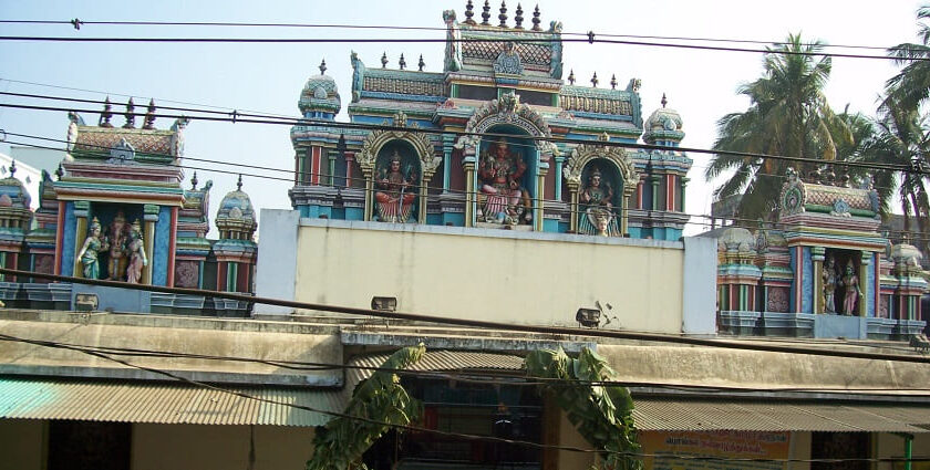 Outside of Vekkaliyamman Temple featuring idols of deities and an entrance decorated with leaves hanging.