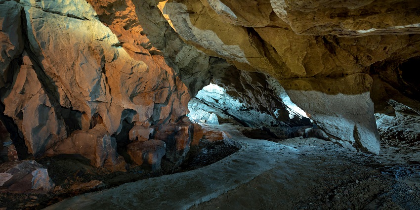 Inside of a cave showing rock formations and a dark passageway.