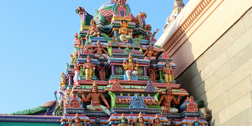 Looking up at a layered concrete structure painted in earthy brown and green tones