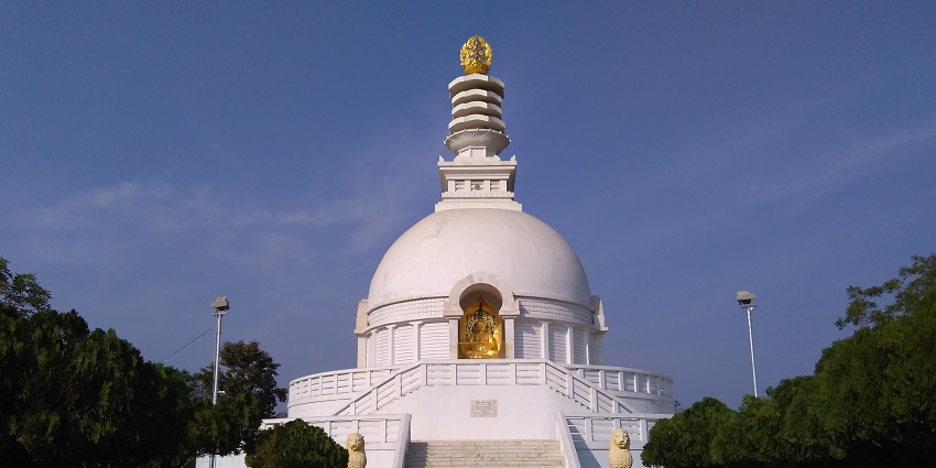 Front view of the Stupa with golden statues and two guardian lions at the entrance.