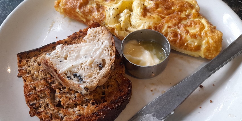 A picture of a delectable breakfast with omelette and bread served at Auroville Bakery