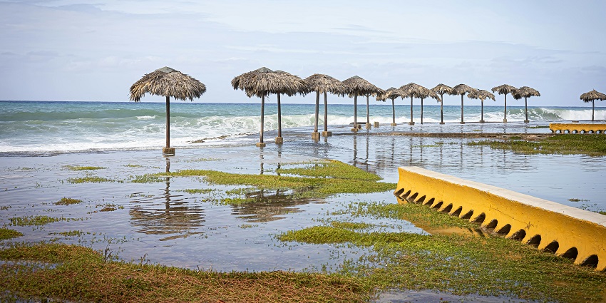 A picture of a beautiful beach submerged by the sea with hut umbrellas.