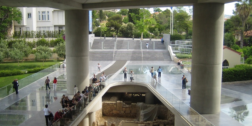 A crowd of people seeing the ruins at the new Acropolis Museum near the entrance.