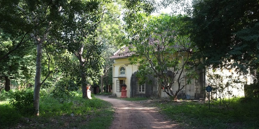 The Theosophical Society building in Adyar, Chennai, India, showcasing its architectural style amidst greenery.