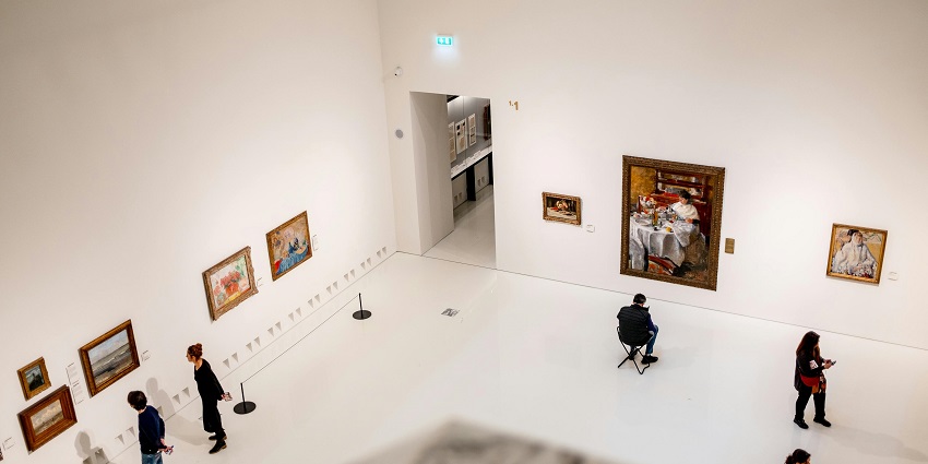 Visitors explore exhibits in a museum, with art displays and a spacious interior.