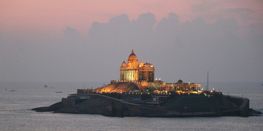 A picture of a building perched upon a rock surrounded by ocean on all sides