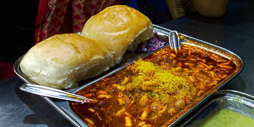 A picture of a famous Maharashtrian dish that goes by the name Misal Pav, served at a restaurant.